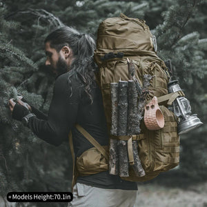 Une personne avec une queue de cheval, portant un sac à dos Spanker 75 L, des bûches, une tasse en bois et une lanterne dans une forêt dense.
