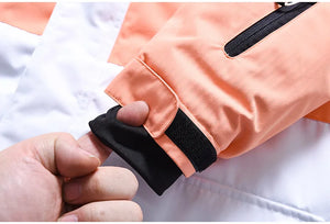 Une personne ajuste le poignet d'une veste en polyester couleur pêche « Artic King - Queen 105 » avec une doublure intérieure noire et une poche zippée visible.