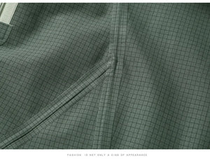 Gros plan sur le tissu à carreaux verts avec coutures apparentes et détails de fermeture éclair, doté d'une finition imperméable conçue pour les amateurs de plein air. Le texte en bas dit : "LA MODE N'EST PAS SEULEMENT UNE GENRE D'APPARENCE". Mise en valeur de la Veste de randonnée / hardshell imperméable pour homme 260g "KUCLUT - Arder" de KUCLUT.