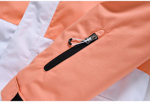 Gros plan de la manche de la veste de ski et de snowboard d'hiver unisexe « Artic King - Queen 105 », fabriquée en polyester durable orange et blanc, présentant une poche zippée en diagonale avec une fermeture éclair noire et une languette de traction.