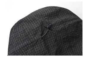 Gros plan d'un tissu noir à motif quadrillé, faisant partie de la veste de randonnée coupe-vent pour homme Simwood résistante à l'eau « SIMWOOD - SM130288 », montrant un bloque-cordon avec un clip de réglage au milieu.