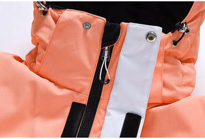 Gros plan de la veste orange Artic King « Queen 105 » habilement confectionnée en polyester résistant, présentant une fermeture éclair noire et un rabat blanc fixé par des boutons-pression.
