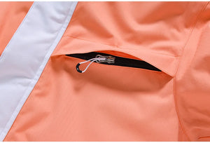 Gros plan de la veste en polyester orange de la combinaison d'hiver unisexe « Artic King - Queen 105 », dotée d'une poche zippée noire partiellement ouverte, avec un cordon blanc attaché à la tirette de la fermeture éclair.
