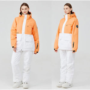 Vêtue de la veste d'hiver bicolore orange et blanche « Artic King - Queen 105 » en polyester résistant, avec un pantalon blanc assorti, une personne se tient debout et pose sous deux angles comme un modèle de la collection Artic King.