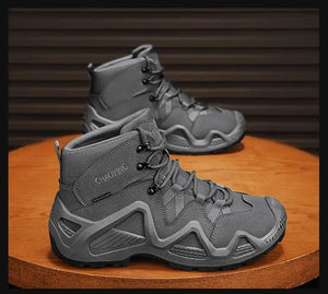 Une paire de bottes tactiques imperméables et respirantes pour homme Hunting Chaoying "Hunting Chaoying - Y0711" grises avec lacets noirs sont présentées sur une surface ronde en bois sur un fond sombre rayé.