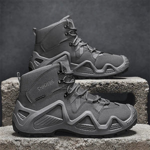 Deux bottes tactiques grises "Hunting Chaoying - Y0711" de la marque DQTBE, imperméables et respirantes, sont présentées côte à côte sur des blocs en béton—idéales pour toutes les aventures masculines.