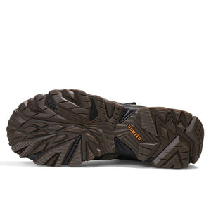 A pair of HUMTTO Chaussures de randonnée mid-top "HT-210626A" pour homme avec protection splash-proof, cuir véritable, semelle caoutchouc robuste, panneaux mesh et fermeture lacets, marron/noir avec accents verts, sur fond blanc.