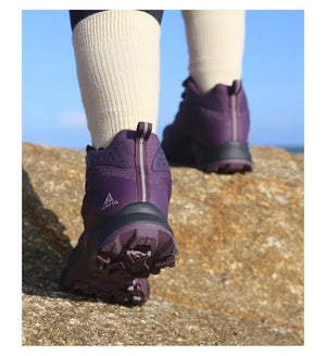 Une chaussure de randonnée pour femmes HUMTTO - HT-220838B violette avec protection contre les éclaboussures, semelle robuste, soutien de la cheville et système de laçage rapide, représentée sur un fond blanc avec le logo Humtto dans le coin supérieur gauche.