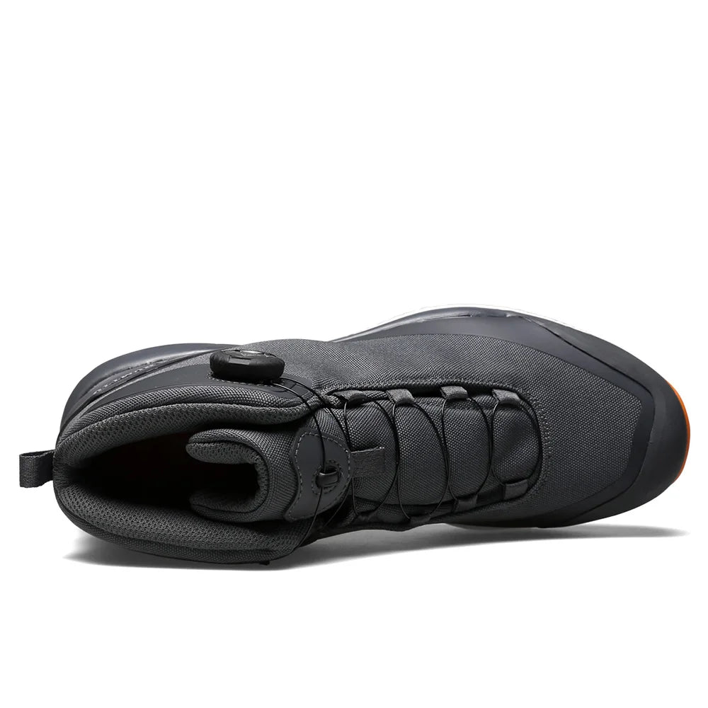 Les chaussures de randonnée Humtto HT-220838A pour hommes sont dotées d'une protection contre les éclaboussures, d'un système de laçage à cadran, d'un design gris et noir avec une bande de roulement orange, de logos visibles, et sont des chaussures de randonnée parfaites pour les sentiers accidentés.