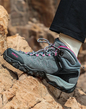 Les HUMTTO - HT-290027B mid-top randonnée bottines pour femme, en gris et noir avec accents roses, sont présentées en angle sur fond blanc. Elles offrent une protection splash-proof et une semelle antidérapante pour plus d'adhérence.