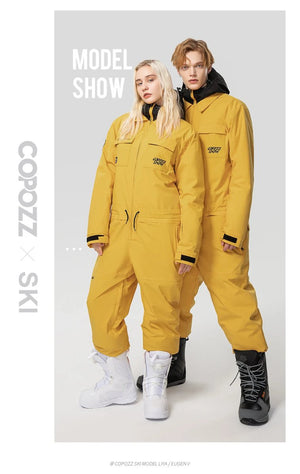 Deux mannequins portent la combinaison de ski imperméable Copozz Jump suit 21306 jaune et des boots sur fond uni.