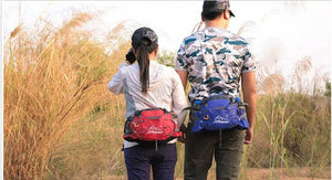 Deux personnes se tiennent dans un champ herbeux, dos tourné, portant casquettes et sacs à dos unisexes. Elles sont prêtes à tout avec leur équipement Kendome résistant et imperméable, notamment le sac de taille imperméable et bandoulière compatible 10 L « Kendome - Artic Mountain », offrant une protection imperméable en rouge ou en bleu.