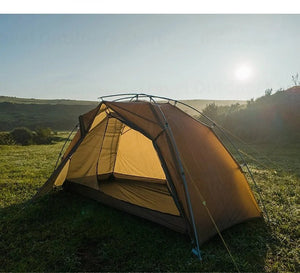 Tente de bivouac / bikepacking ultra-légère 3F UL GEAR, double-parois avec arceaux en aluminium, posée sur un terrain herbeux avec des collines et un soleil levant en arrière-plan.