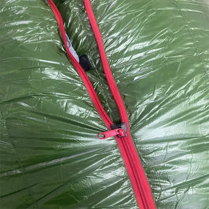 Un sac de couchage d'extérieur vert FLAME'S CREED avec fermetures éclair rouges.