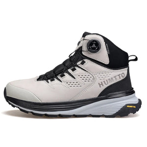 La HUMTTO - HT-240217C est une chaussure de randonnée mid-top noire pour homme avec cuir de vache durable, doublure polaire, technologie Static Waterproof, semelle épaisse, côtés texturés et système de laçage à molette, présentée sur un fond blanc.