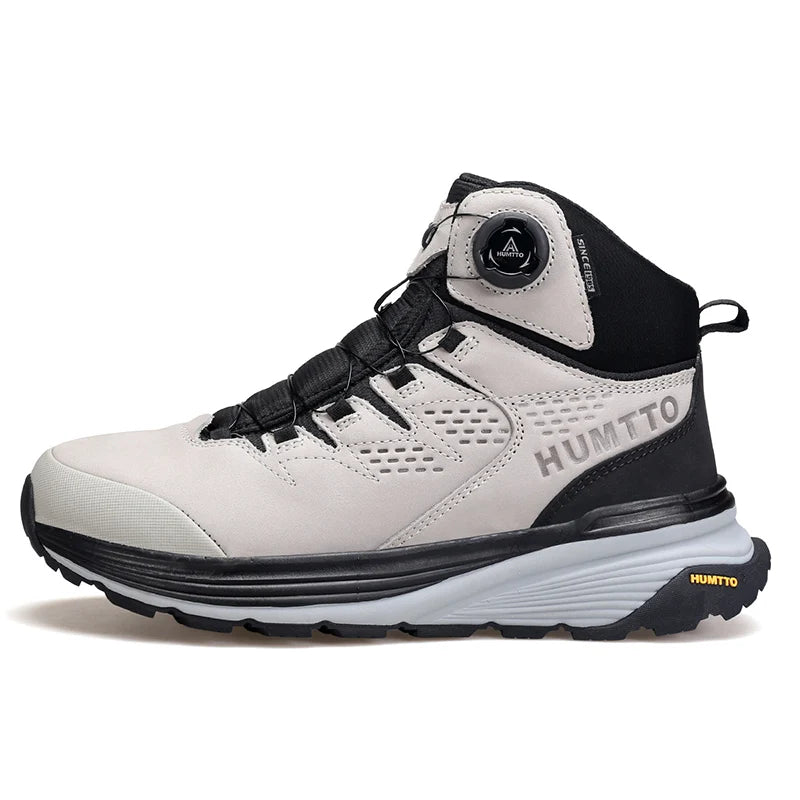 La HUMTTO - HT-240217C est une chaussure de randonnée mid-top noire pour homme avec cuir de vache durable, doublure polaire, technologie Static Waterproof, semelle épaisse, côtés texturés et système de laçage à molette, présentée sur un fond blanc.