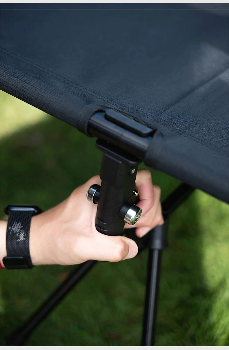 A Lit de camp 2 en 1 avec tente simple-paroi "Wellhike Minimalism - Yunchi SWS" de Wellhike Minimalism est installé sur l'herbe, avec des tables pliantes à proximité. Le texte "WELLHIKE minimalism" apparaît en bas de l'image.