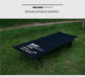 A Lit de camp 2 en 1 avec tente simple-paroi "Wellhike Minimalism - Yunchi SWS" de Wellhike Minimalism est installé sur l'herbe, avec des tables pliantes à proximité. Le texte "WELLHIKE minimalism" apparaît en bas de l'image.