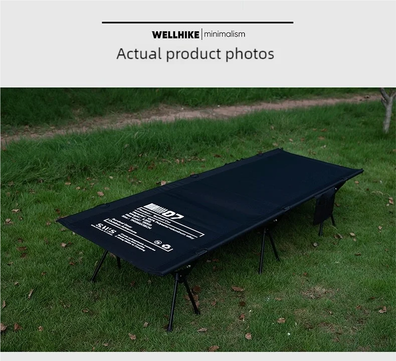 A Lit de camp 2 en 1 avec tente simple-paroi "Wellhike Minimalism - Yunchi SWS" de Wellhike Minimalism est installé sur l'herbe, avec des tables pliantes à proximité. Le texte "WELLHIKE minimalism" apparaît en bas de l'image.