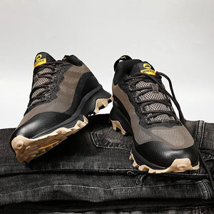 Chaussures de randonnée basses HIKEUP HK-15 noires et grises, semelles beiges, posées sur un jean denim, fond uni.
