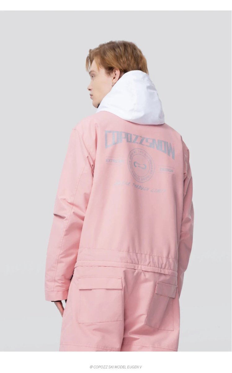 Personne cheveux châtains porte la combinaison ski waterproof Copozz Jump suit 21306 rose et blanc, dos à fond gris clair.