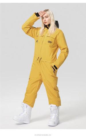 Personne en combinaison ski imperméable Copozz Jump suit 21306 jaune et bottes blanches, debout sur fond clair.