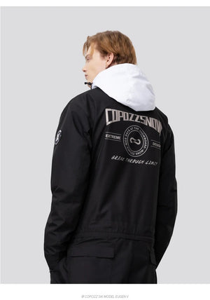 Personne portant la combinaison de ski imperméable Copozz Jump suit 21306 noire à capuche blanche, fond gris neutre.