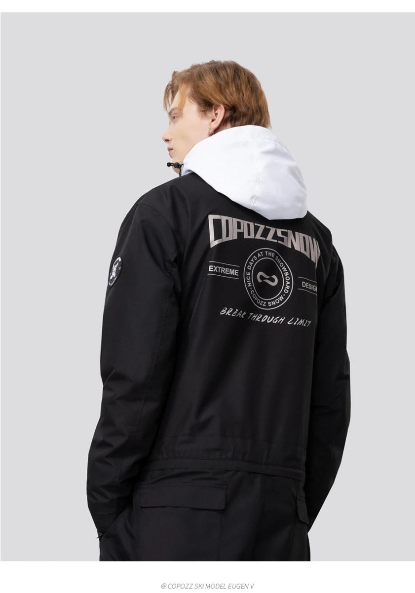 Personne portant la combinaison de ski imperméable Copozz Jump suit 21306 noire à capuche blanche, fond gris neutre.