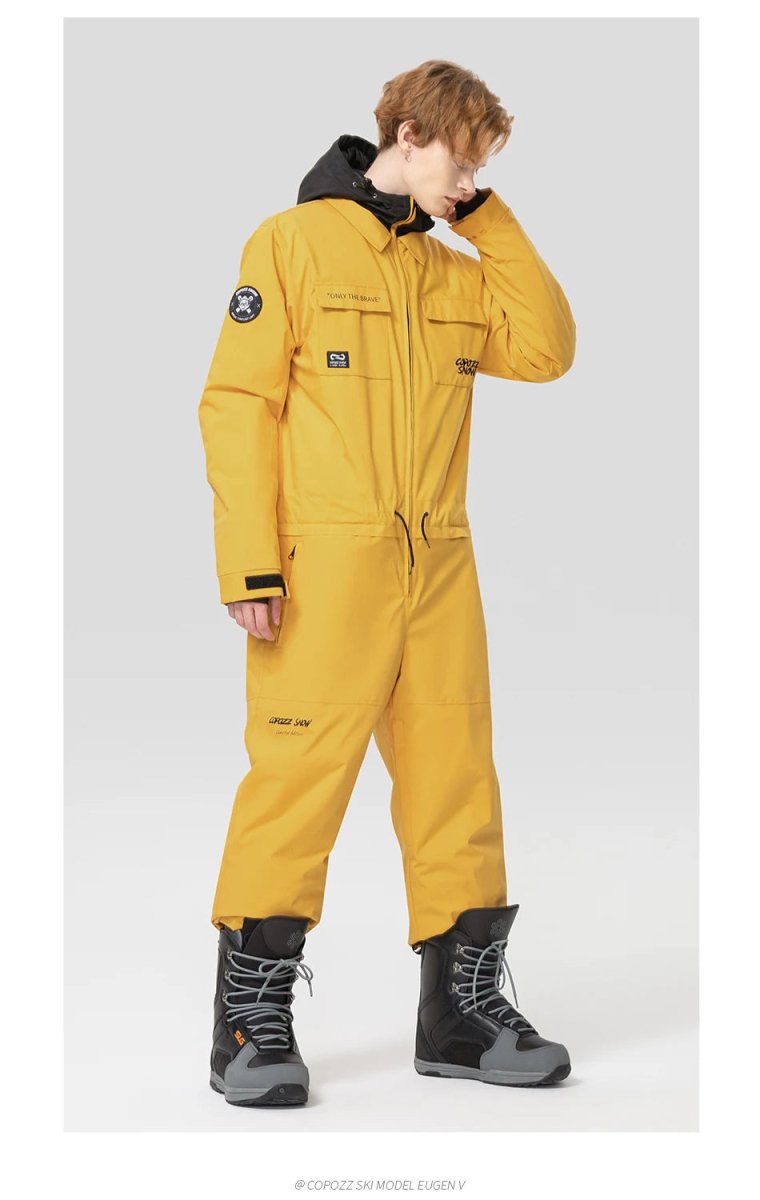 Personne en Copozz Jump suit 21306 imperméable, gants noirs, bottes neige gris-noir, prête pour le ski ou snowboard.