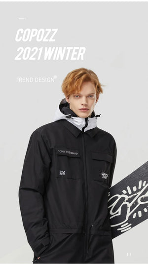 Jeune homme aux cheveux clairs en combinaison de ski Copozz imperméable Jump suit 21306, tenant un snowboard devant le logo Copozz.