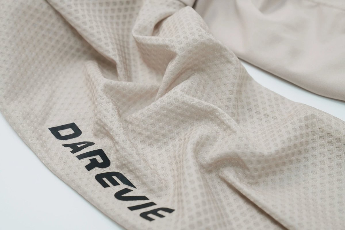Le maillot de cyclisme unisexe à manches longues blanc DAREVIE "DVJ187" est doté d'une protection UV-SPF30+/SPF50+, d'une fermeture éclair sur le devant, de logos discrets, d'un tissu respirant et de manches en maille 3D pour plus de confort. Montré sur un fond uni.